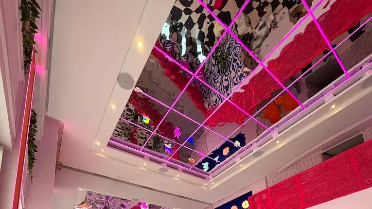 Le plafond en dalles de miroir cernées de néons roses